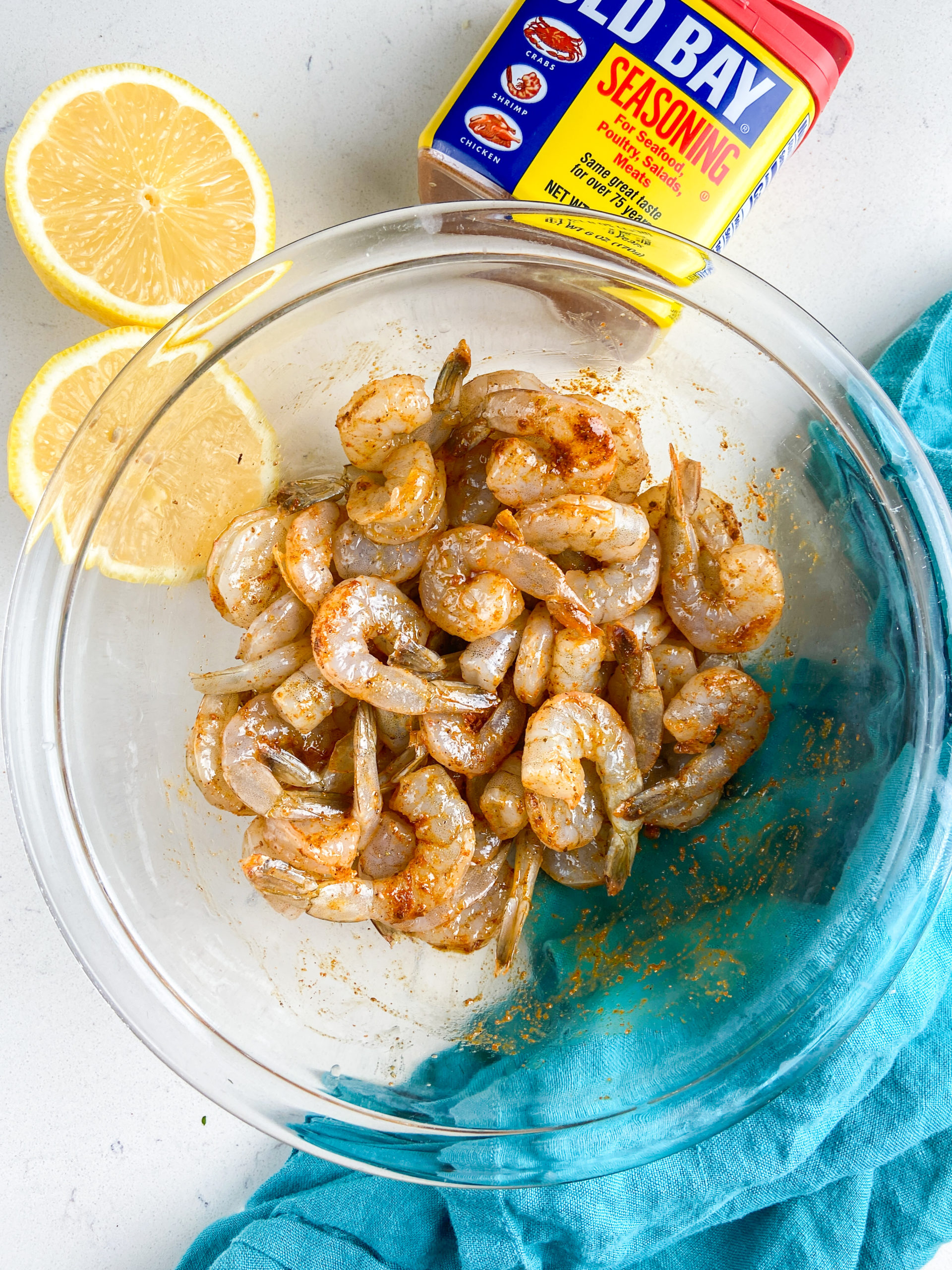 Overhead photo of shrimp mixed with old bay seasoning and olive oil. 