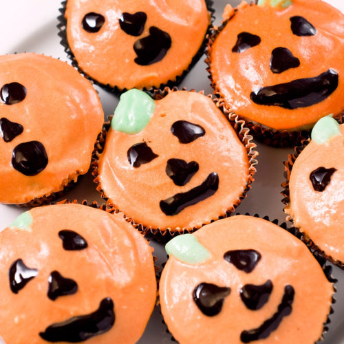 jack o lantern cupcakes on white plate.