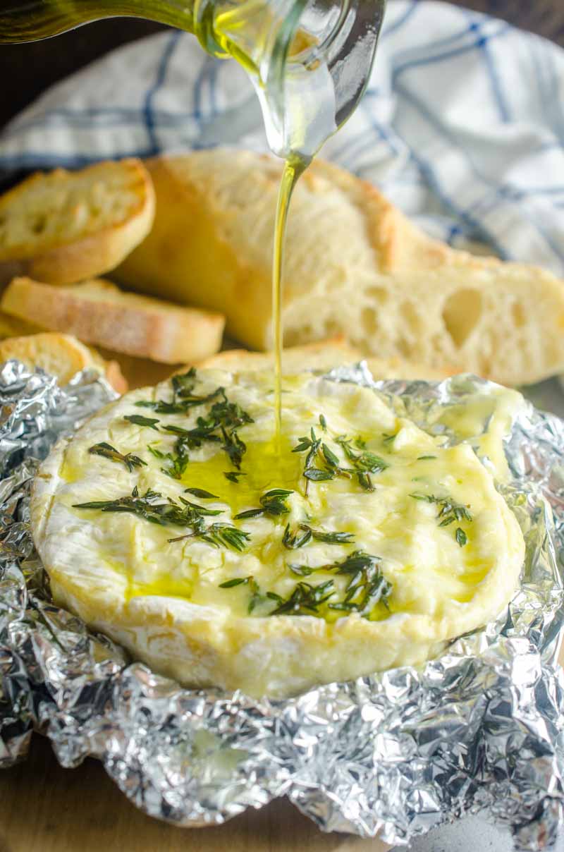 Camembert au four parsemé d'ail frais, de thym et d'un filet d'huile d'olive. C'est le rêve de tout amateur de fromage ! Servir avec des craquelins et des crostini.